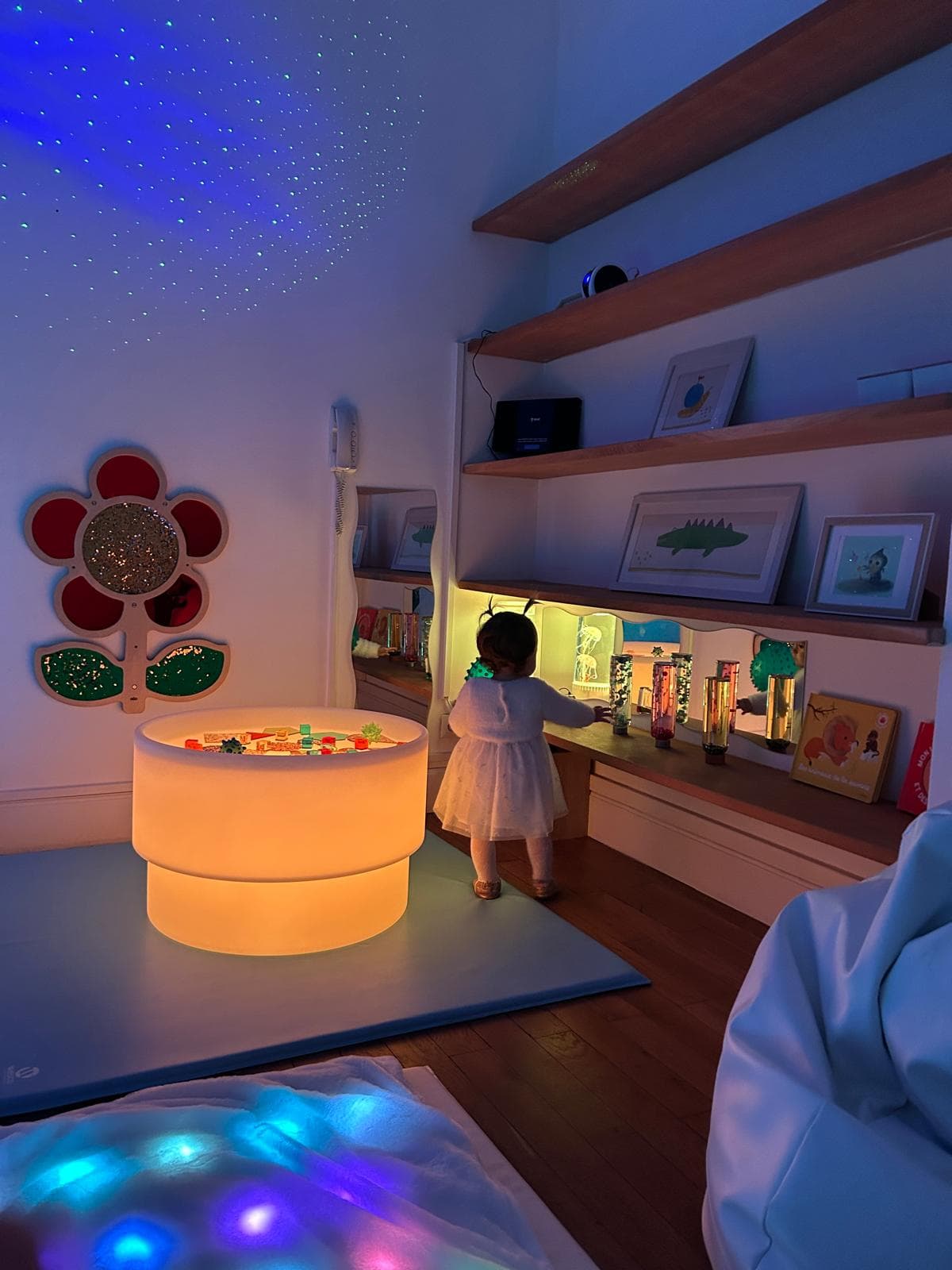 Enfant découvrant les étagères sensorielles dans une ambiance bleue