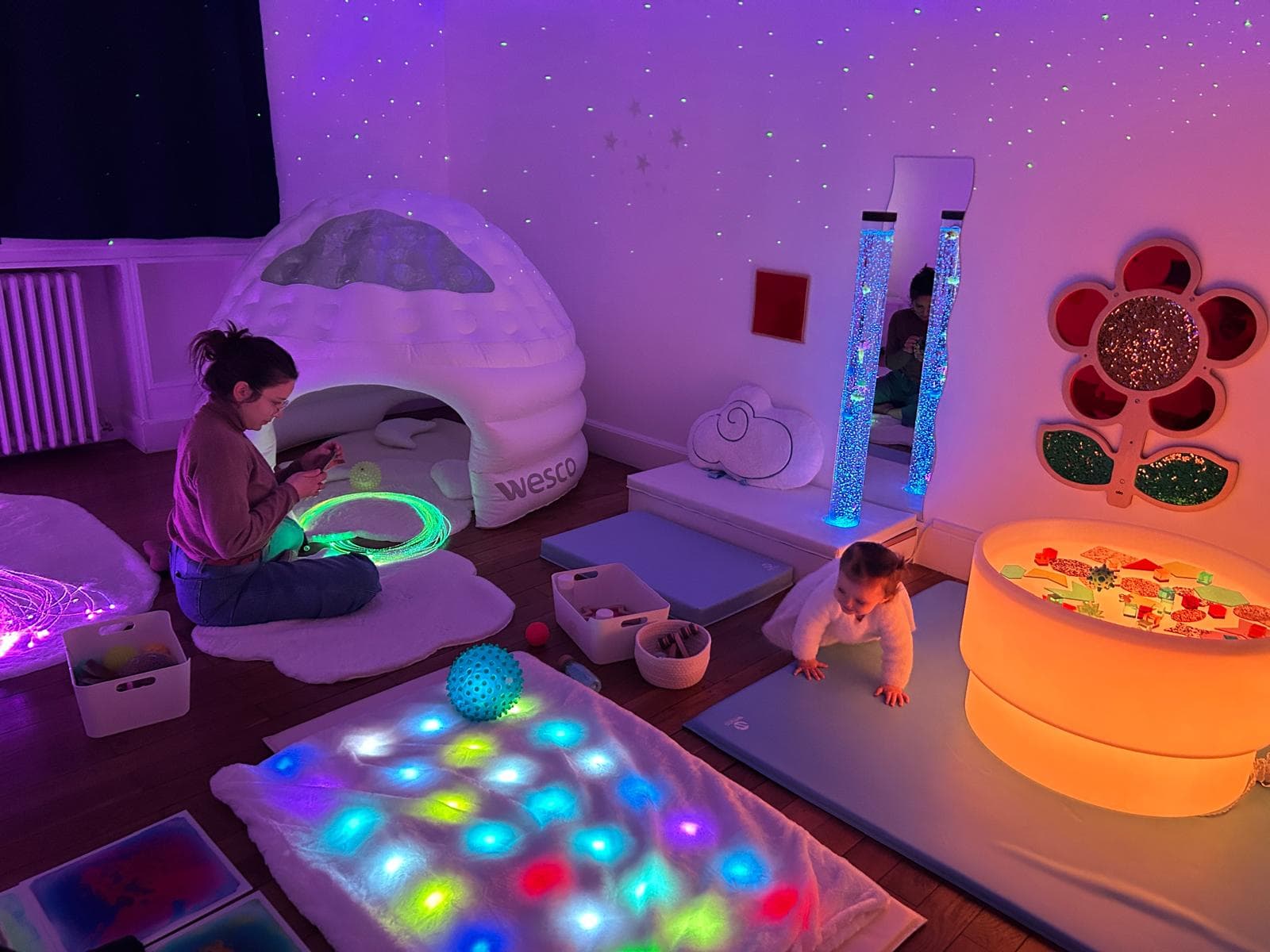 Salle principale Snoezelen avec maman, fibres optiques et enfant explorant